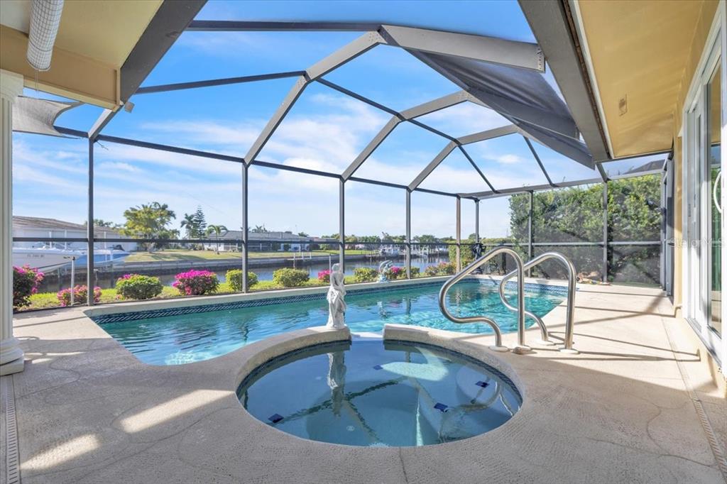A screened-in pool and hot tub area overlooking a canal with a boat dock — 1109 APPIAN DRIVE, PUNTA GORDA, FL