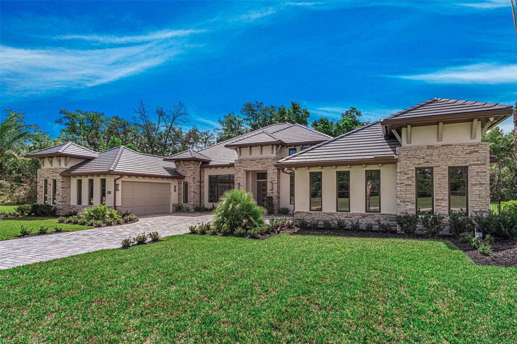 A single-story house with a stone facade, tile roof, and a paved driveway — 1861 ADRIAN CREEK BLVD, PORT ORANGE, FL