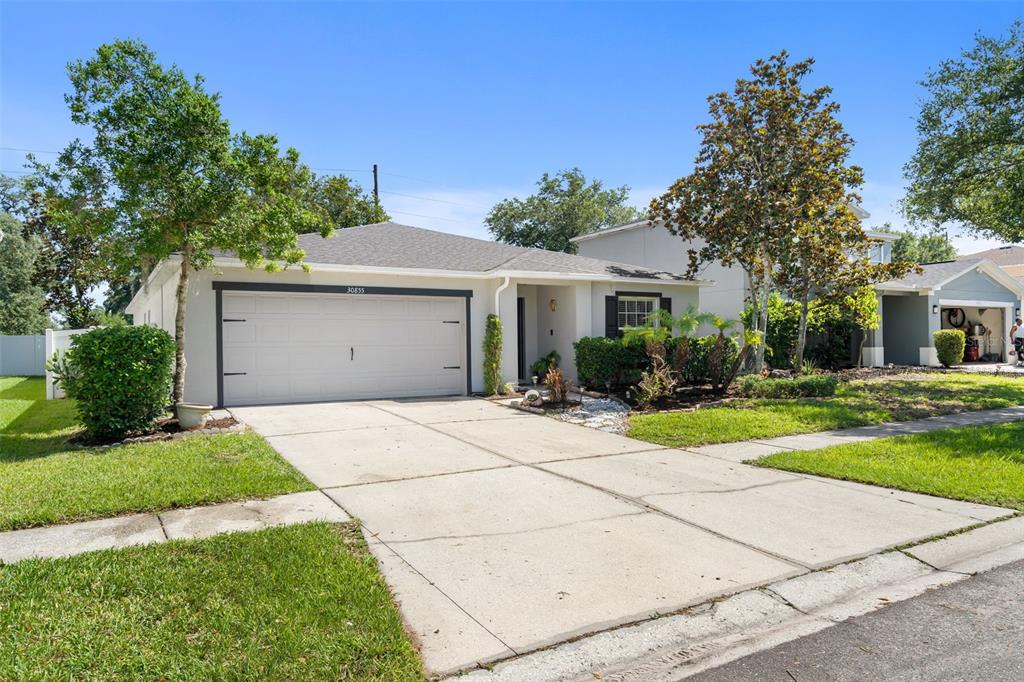 A single-story house with a two-car garage, concrete driveway, and front yard landscaping — 30855 TEMPLE STAND AVENUE, WESLEY CHAPEL, FL