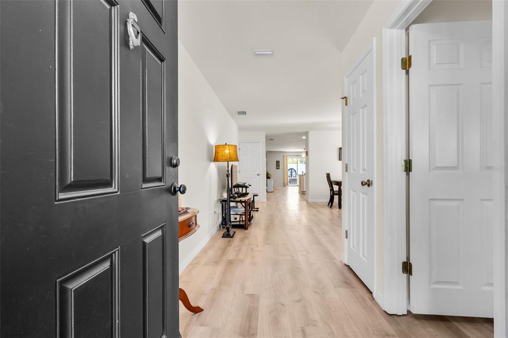 A view from an open front door into a hallway with light wood-look flooring — 30855 TEMPLE STAND AVENUE, WESLEY CHAPEL, FL