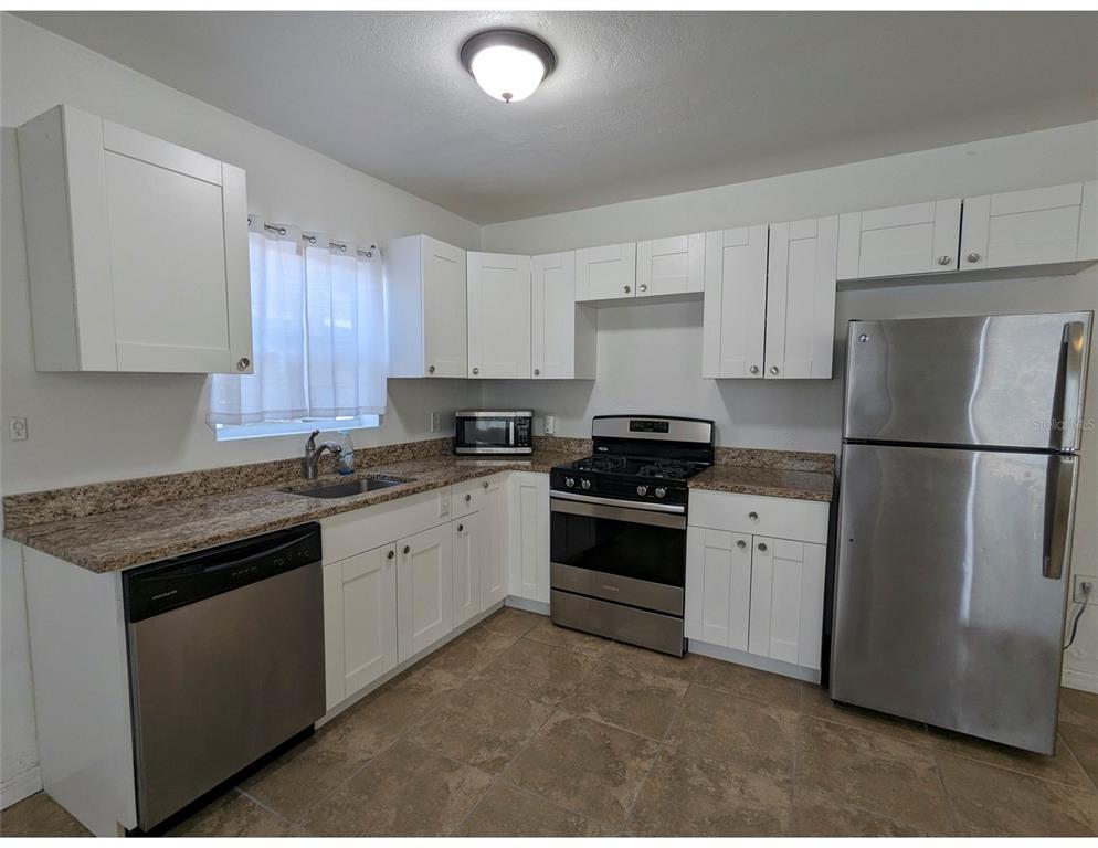 A kitchen features white cabinets, granite countertops, stainless steel appliances, and tile flooring — 411 S ALBANY AVENUE UNIT 3, TAMPA, FL