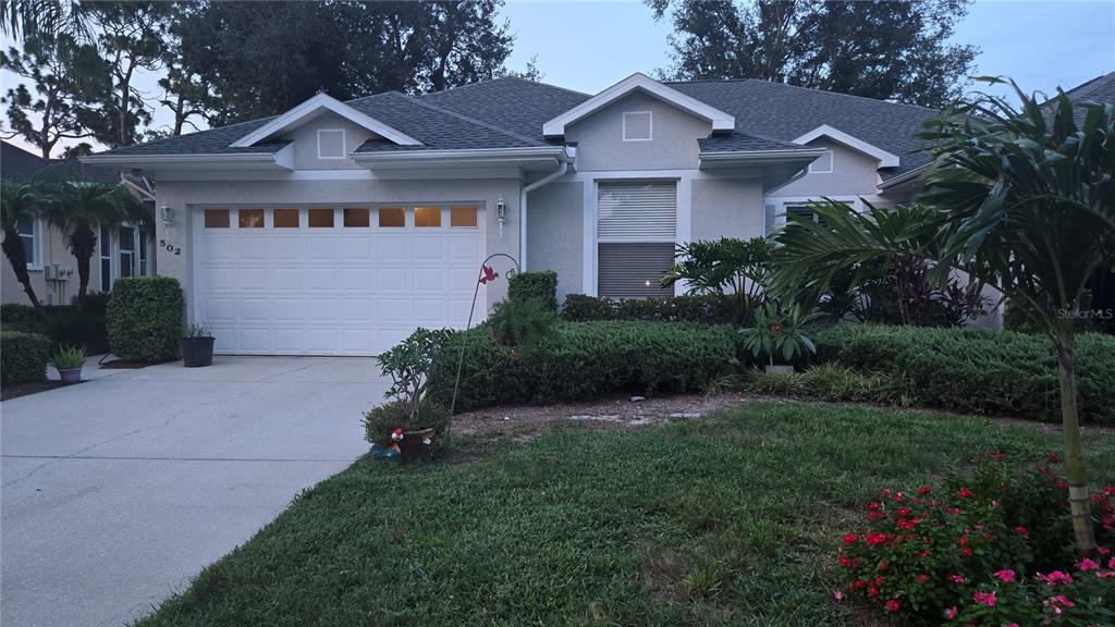 A single-story house with a white garage door, gray roof, and landscaped front yard — 502 CATALINA ISLES CIRCLE, VENICE, FL