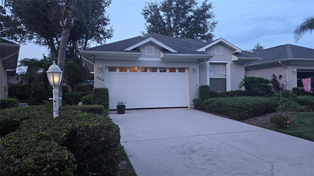 A single-story house with a white garage door, a concrete driveway, and surrounding landscaping — 502 CATALINA ISLES CIRCLE, VENICE, FL