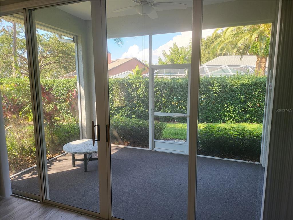 A view through sliding glass doors onto a screened-in patio with a small round table — 502 CATALINA ISLES CIRCLE, VENICE, FL