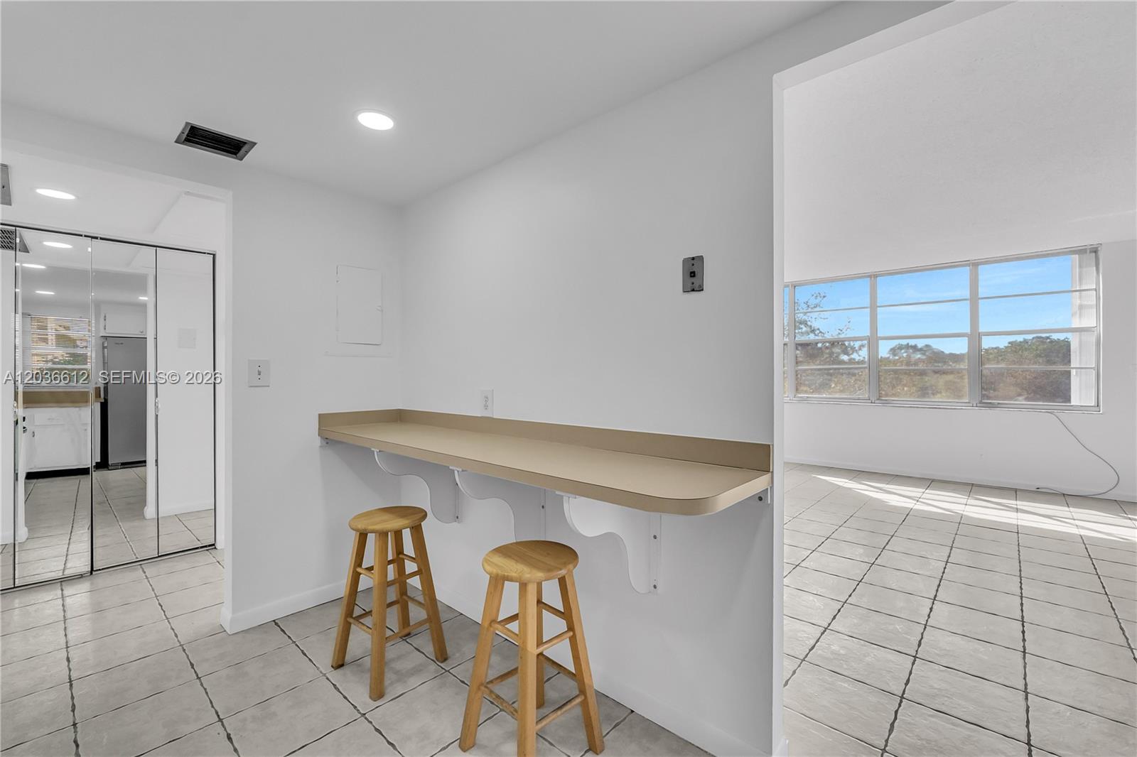 A kitchen breakfast bar with two wooden stools sits against a wall near a windowed room — 2781 Taft St # 303, Hollywood FL 33020, HOLLYWOOD, FL