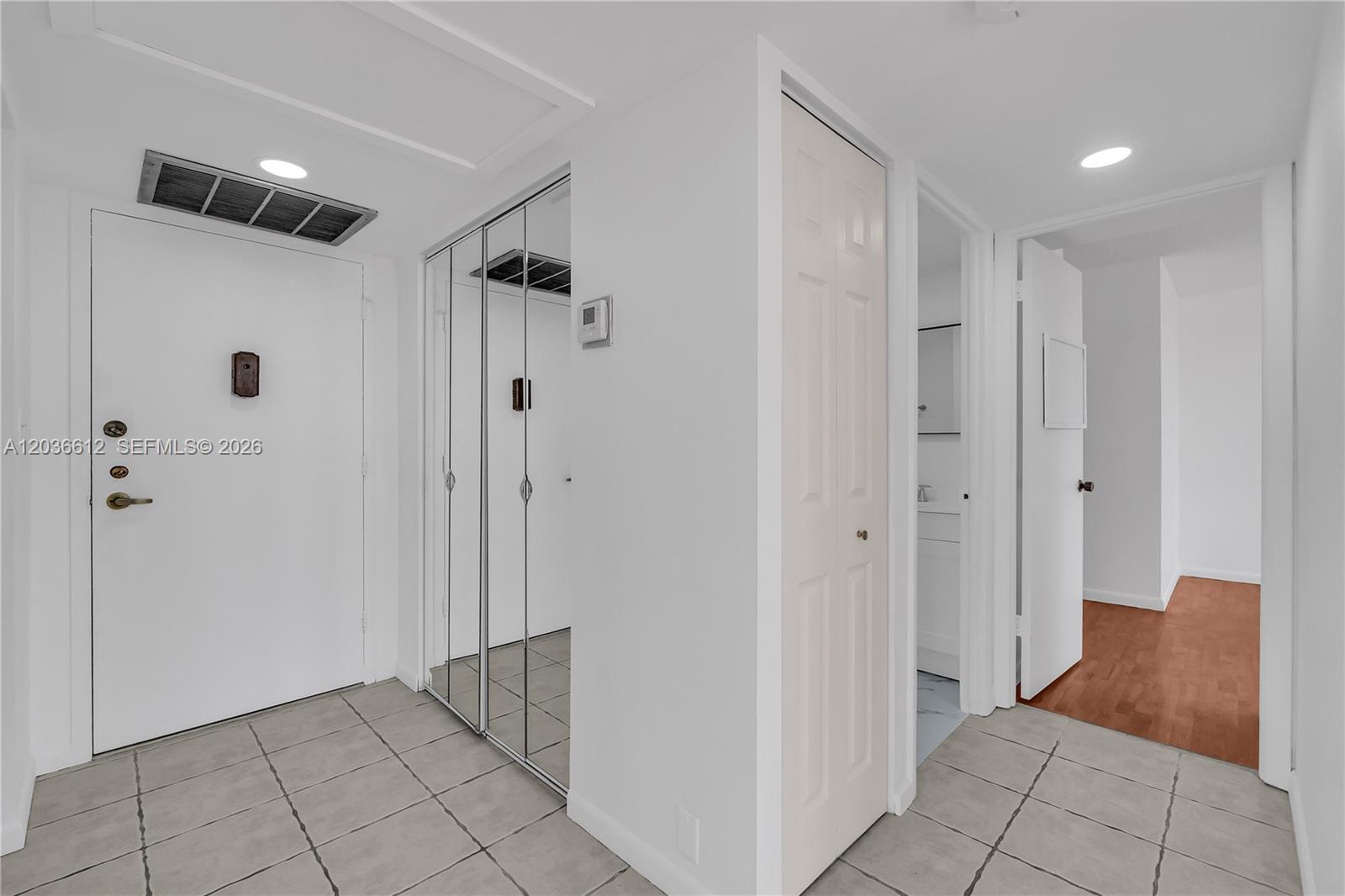 A white entryway features tiled floors, a mirrored closet, and a doorway leading to rooms — 2781 Taft St # 303, Hollywood FL 33020, HOLLYWOOD, FL