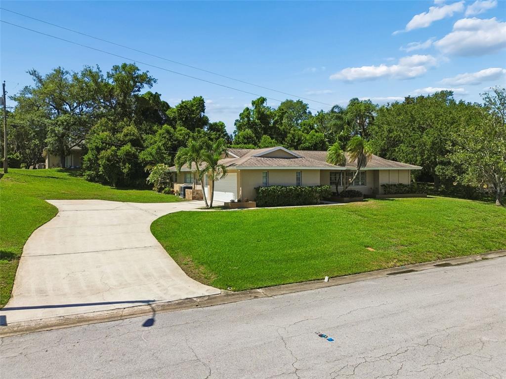 A single-story house with a concrete driveway and a large lawn under a blue sky — 1251 HOLIDAY DRIVE, TARPON SPRINGS, FL