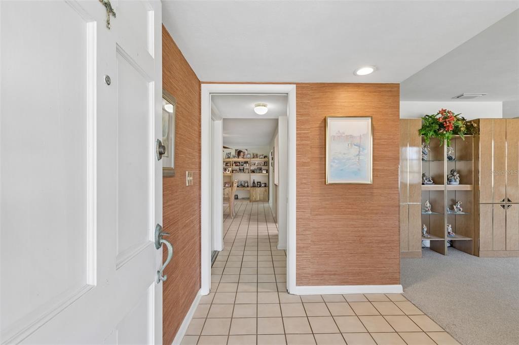 An entryway with tiled floors, textured wallpaper, and a doorway leading to a hallway — 1251 HOLIDAY DRIVE, TARPON SPRINGS, FL