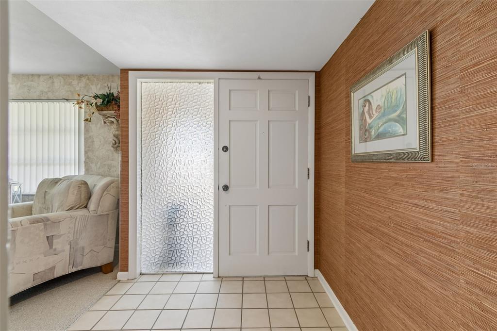 An entryway features a white front door with a textured glass sidelight and grasscloth wallpaper — 1251 HOLIDAY DRIVE, TARPON SPRINGS, FL