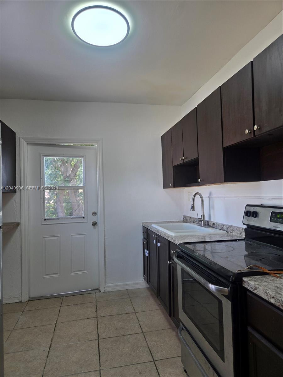 A kitchen features dark wood cabinets, a white sink, a stove, and a back door — 5223 SW 25th St # 0, West Park FL 33023, WEST PARK, FL