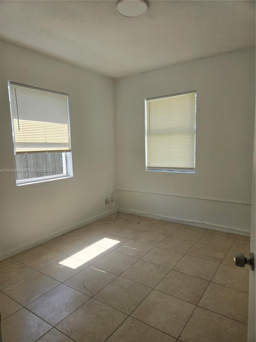 An empty room features white walls, tiled flooring, and two windows with blinds — 5223 SW 25th St # 0, West Park FL 33023, WEST PARK, FL