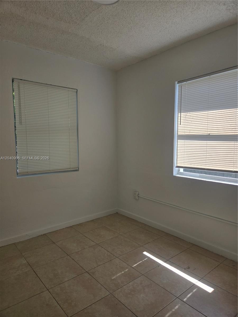 An empty room features white walls, beige tile flooring, and two windows with blinds — 5223 SW 25th St # 0, West Park FL 33023, WEST PARK, FL