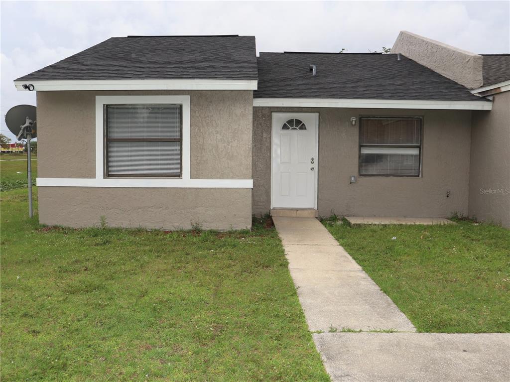 A single-story house with a tan stucco exterior, a white front door, and a walkway — 304 SUN DIAL COURT, COCOA, FL