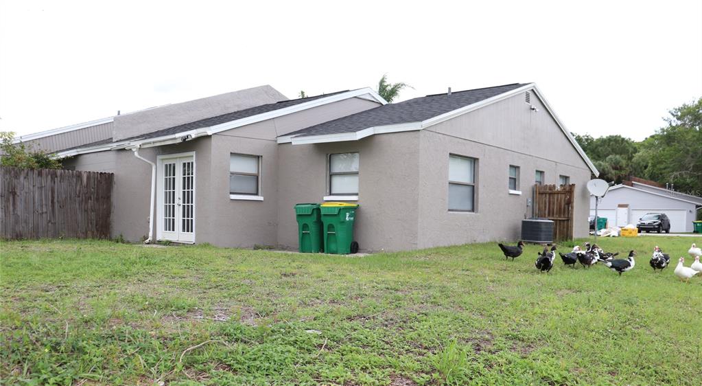 The exterior of a gray house features a backyard with several ducks and two trash cans — 304 SUN DIAL COURT, COCOA, FL