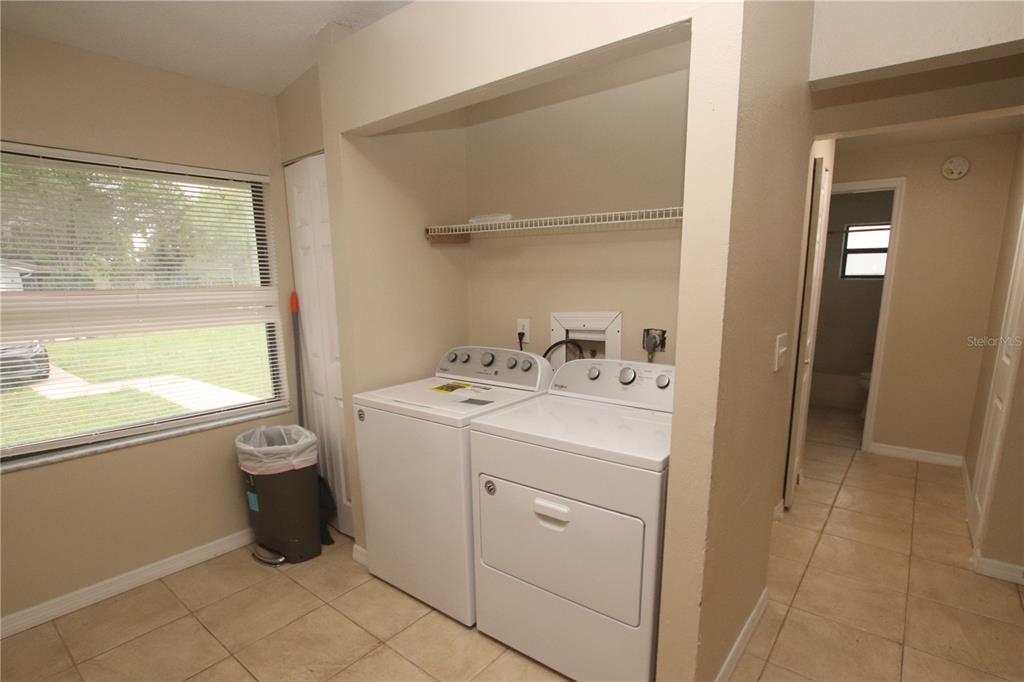 A laundry room with white appliances, tile flooring, and a window with blinds — 304 SUN DIAL COURT, COCOA, FL