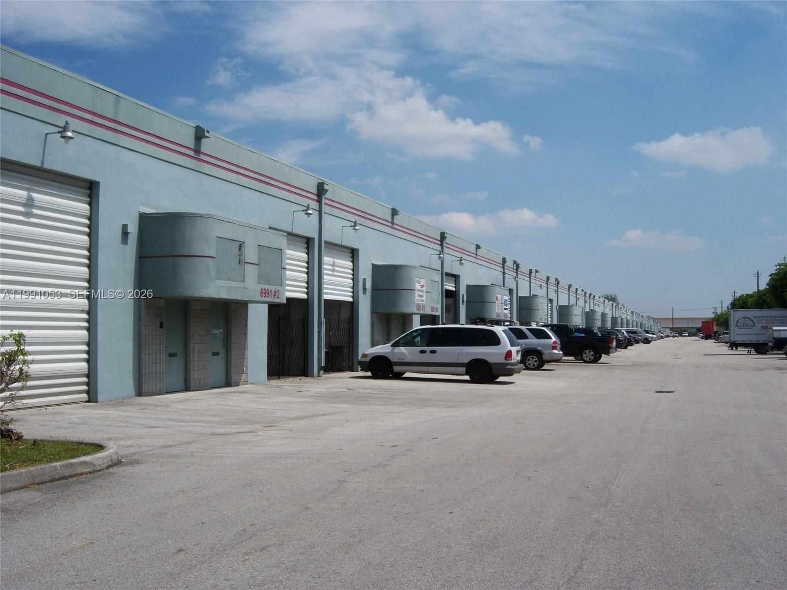 An exterior view of a long, light blue industrial warehouse building with multiple roll-up doors — 6995 NW 82nd Ave # 45, Medley FL 33166, MEDLEY, FL