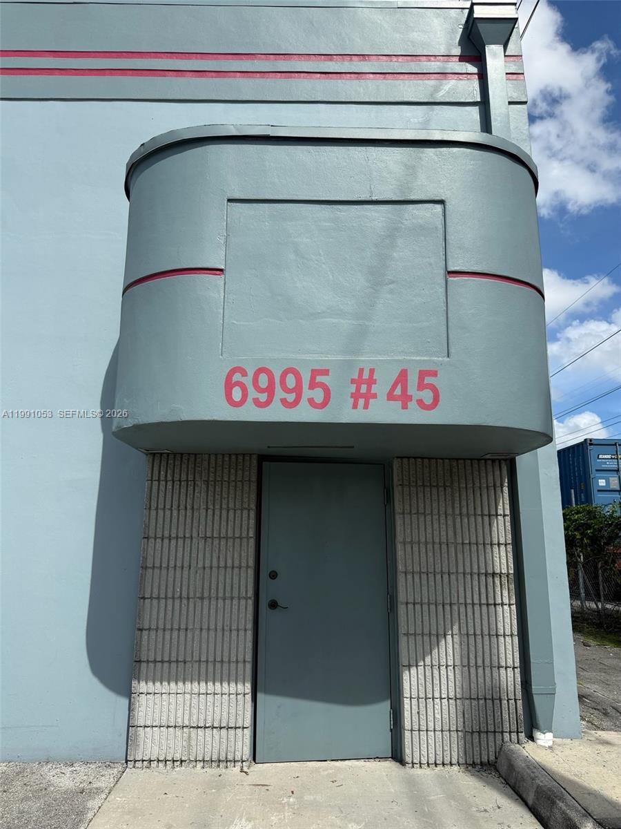 A gray exterior building entrance features a rounded overhang with the address number 6995 #45 — 6995 NW 82nd Ave # 45, Medley FL 33166, MEDLEY, FL