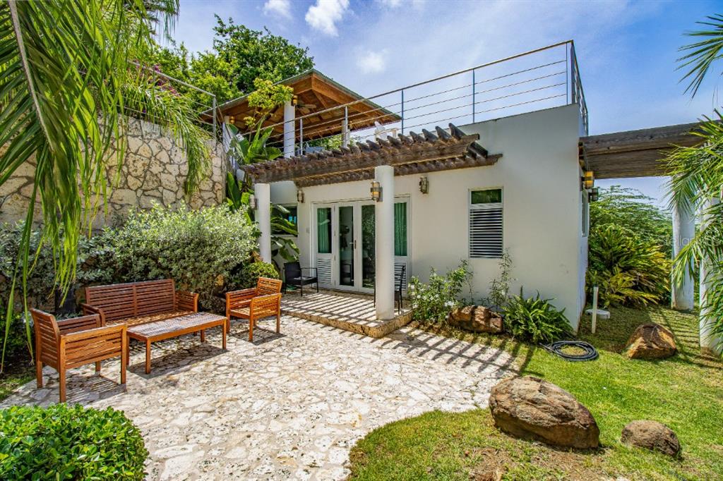 A stone patio with wooden furniture sits in front of a white house with a pergola — BO FLAMENCO LAS QUINTAS SOLAR 15 UNIT Sec La Quintas Solar 15, CULEBRA, PR