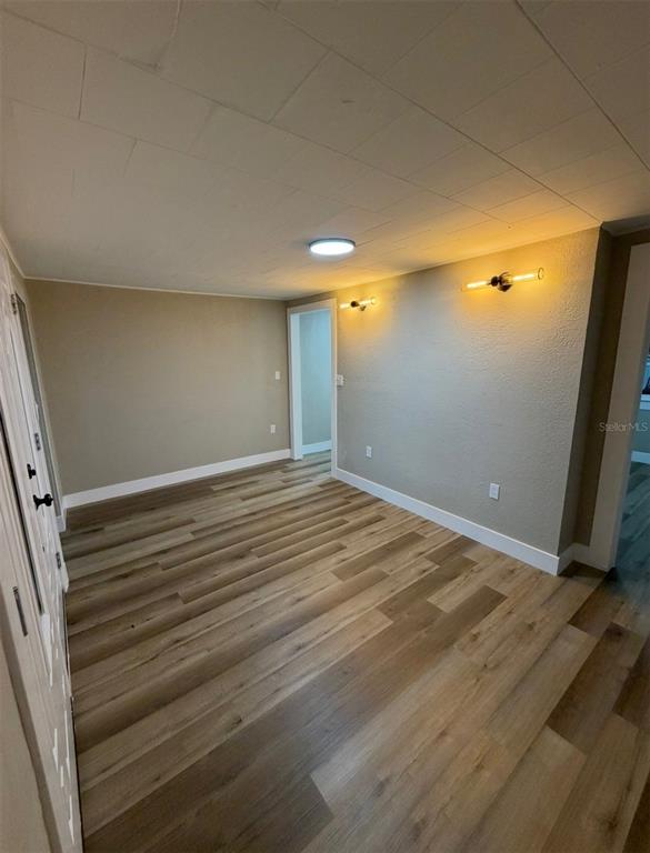 An empty room with light wood-look flooring, beige walls, and two wall-mounted light fixtures — 1221 E DR MARTIN LUTHER KING JR BOULEVARD, TAMPA, FL
