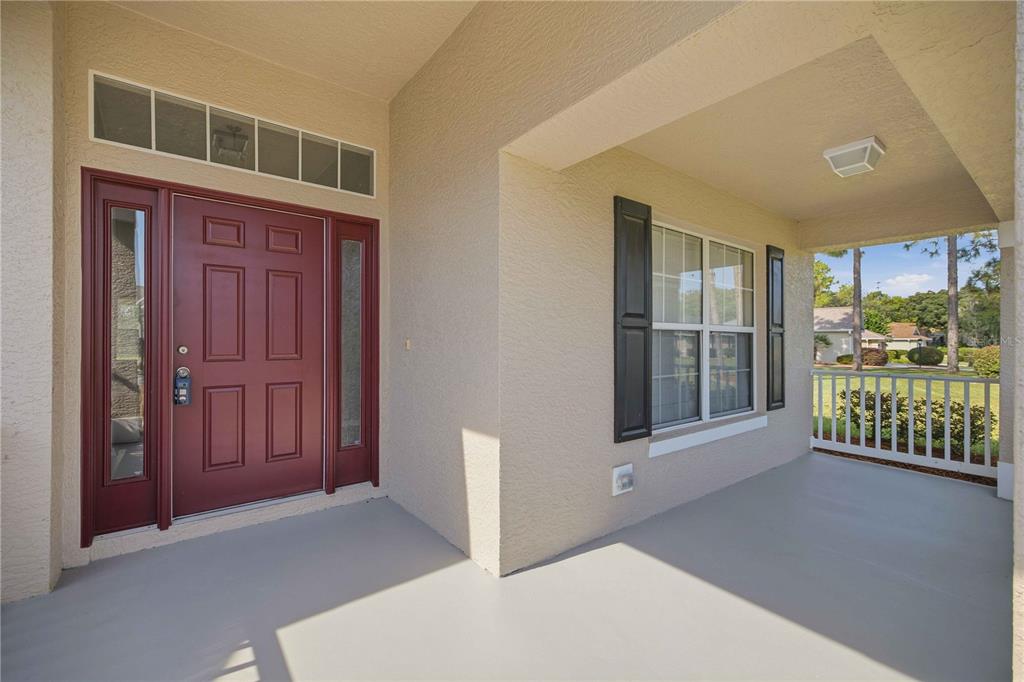 A covered front porch features a red door with sidelights and a window with shutters — 334 LAKE DRIVE, OCALA, FL