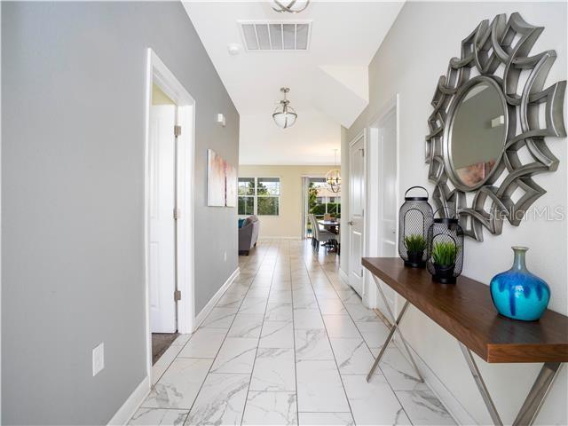A hallway with white marble-look tile floors leads toward a dining area and living room — 1568 MAIDSTONE COURT, DAVENPORT, FL