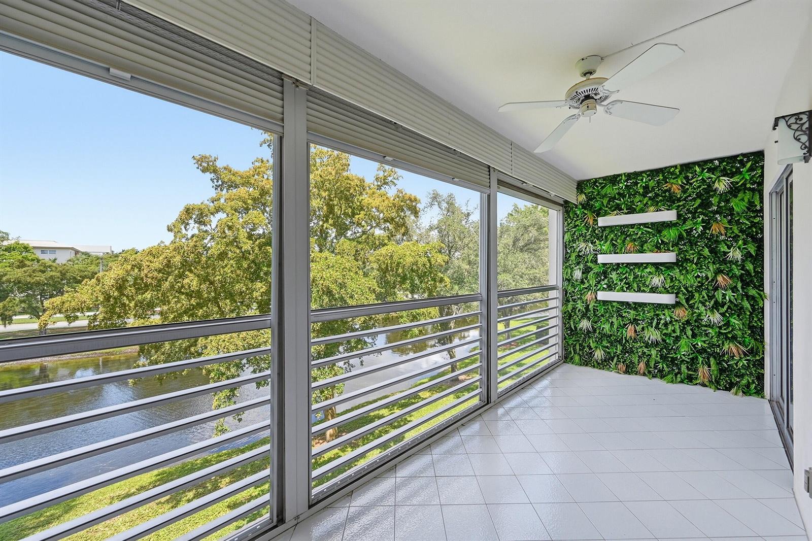 A screened-in balcony features white tile flooring, a ceiling fan, and a green wall panel — 2006 Granada Drive # M3, Coconut Creek FL 33066, COCONUT CREEK, FL