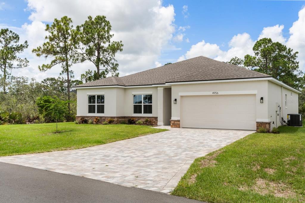 An open-concept living area features wood-look flooring, sliding glass doors, and a white kitchen — 8038 N VOYAGER DRIVE, DUNNELLON, FL