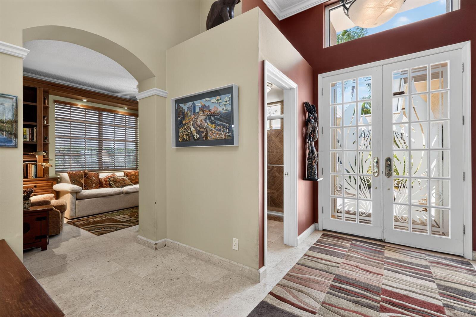 An entryway with a striped rug, double glass doors, and an arched opening to a room — 402 Eagleton Cove Way, Palm Beach Gardens FL 33418, PALM BEACH GARDENS, FL