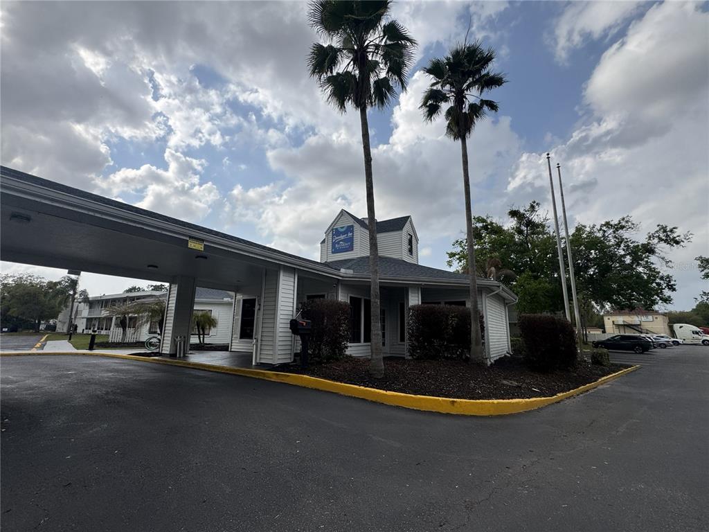 The exterior of a hotel building features a covered entrance, palm trees, and a parking lot — 2930 POLYNESIAN ISLE BOULEVARD UNIT 105, KISSIMMEE, FL