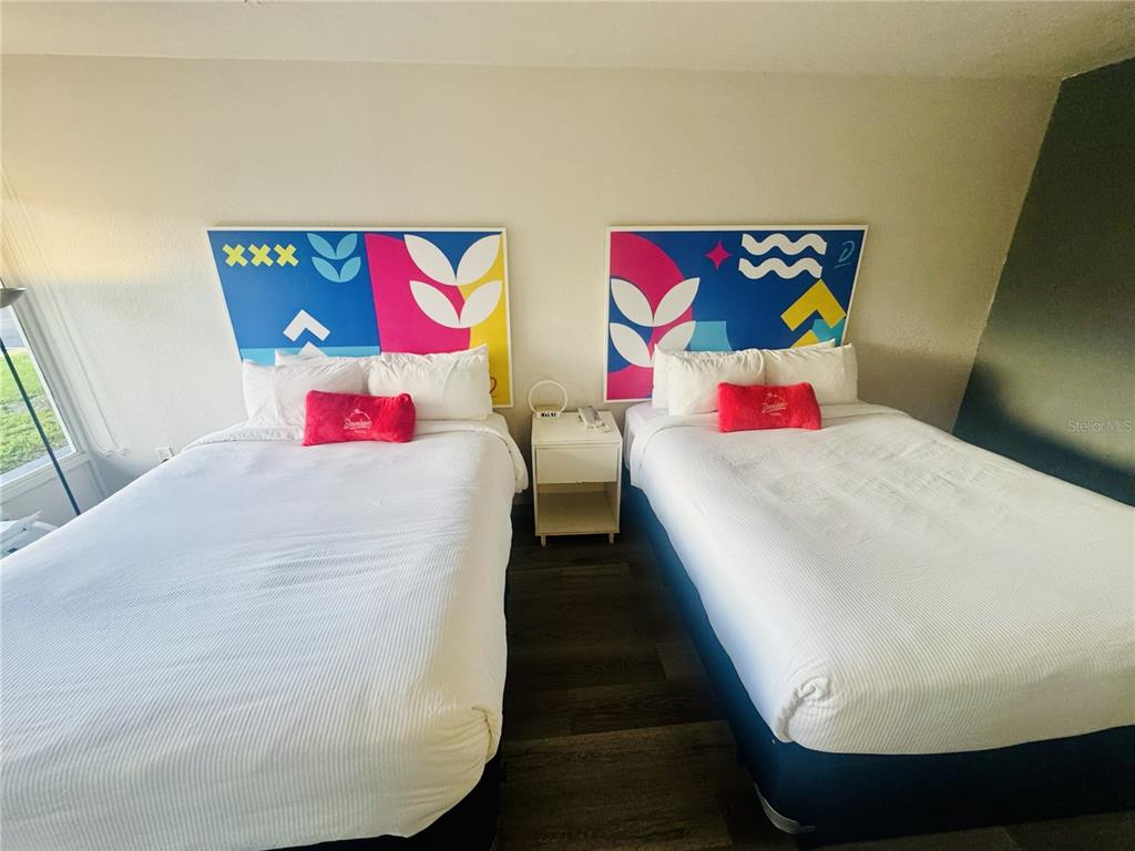 A bedroom features two beds with colorful abstract headboards and a central nightstand — 2930 POLYNESIAN ISLE BOULEVARD UNIT 105, KISSIMMEE, FL