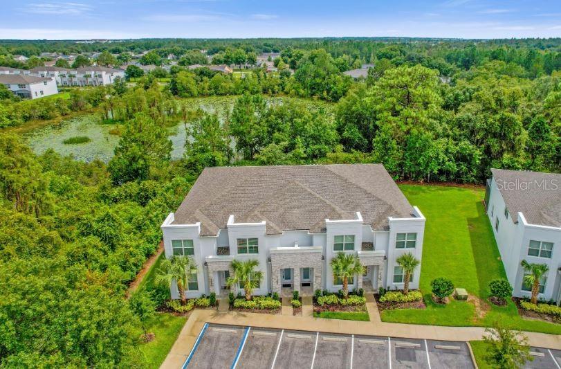 An aerial view shows a multi-unit townhouse building with a parking lot and surrounding greenery — 17350 BLESSING DRIVE, CLERMONT, FL