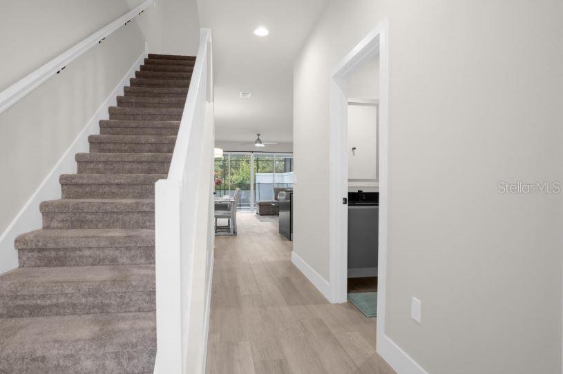 A carpeted staircase leads upstairs next to a hallway with light wood-look flooring — 17350 BLESSING DRIVE, CLERMONT, FL