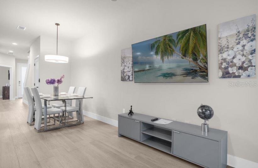 A dining area with a glass table and a living area with a wall-mounted television — 17350 BLESSING DRIVE, CLERMONT, FL