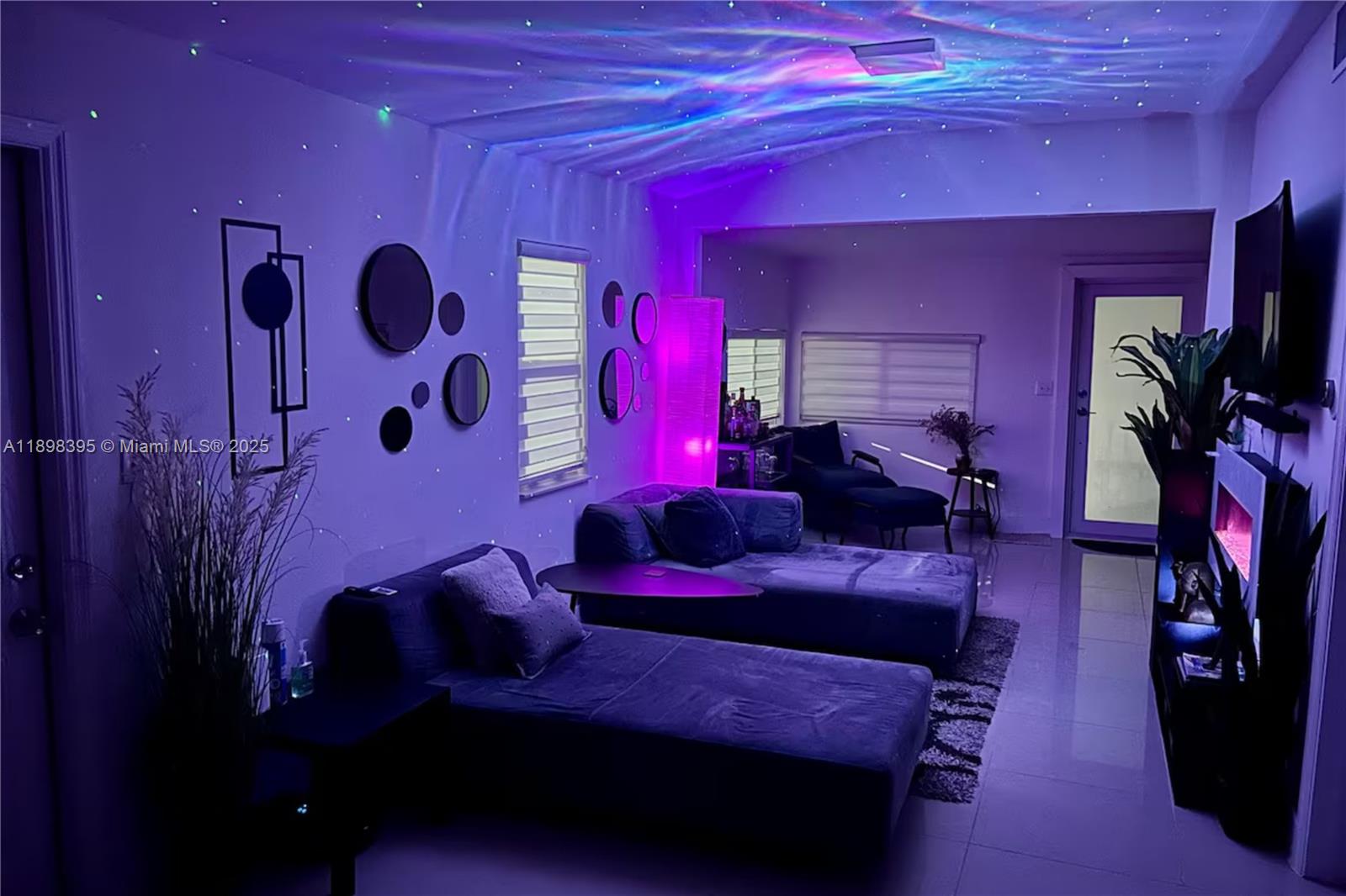 A living room features two dark blue sofas, wall-mounted circular mirrors, and purple ambient lighting — 3132 NW 43rd St, Miami FL 33142, MIAMI, FL
