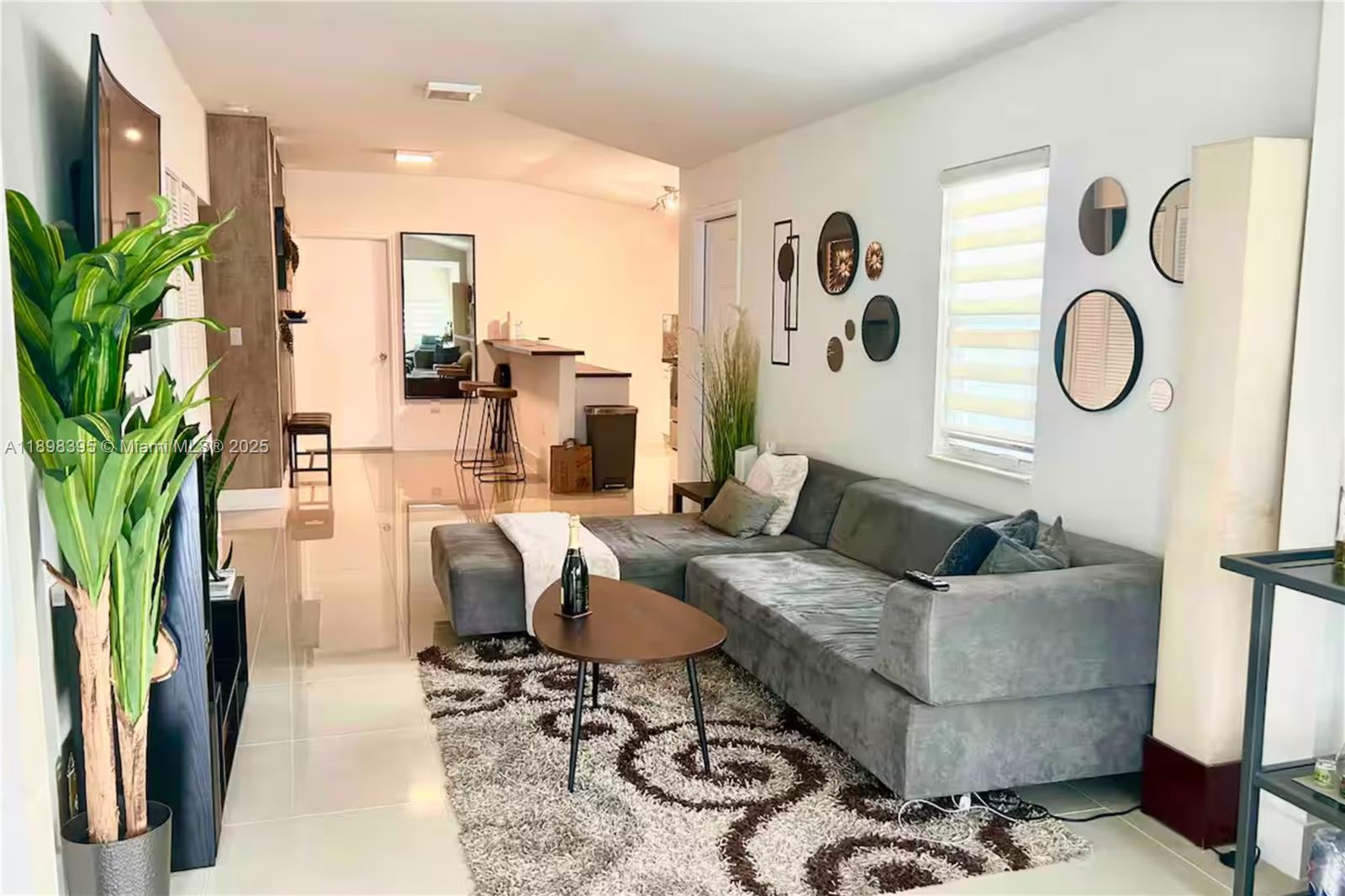 A living room features a grey sectional sofa, a patterned rug, and a breakfast bar — 3132 NW 43rd St, Miami FL 33142, MIAMI, FL