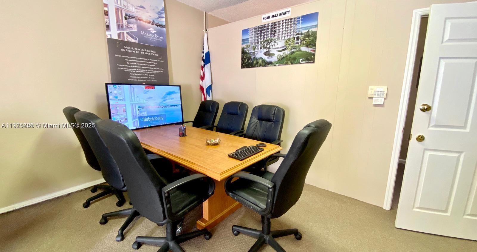 A conference room features a wooden table, five black chairs, and wall-mounted real estate advertisements — 934 S Dixie, Lantana FL 33462, LANTANA, FL