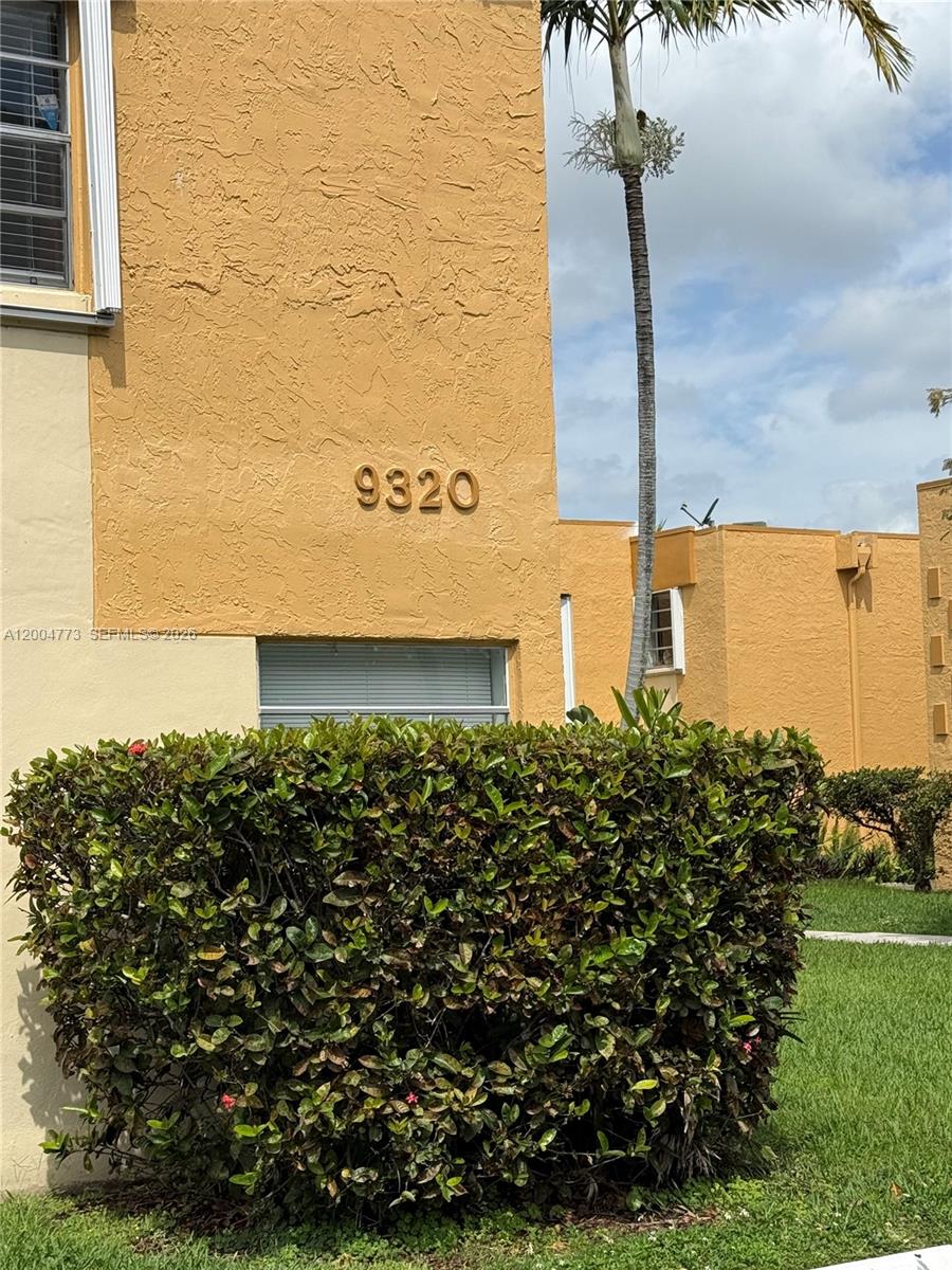 A yellow stucco building exterior features the number 9320 above a window and shrubbery — 9320 W Flagler St # 201D, Miami FL 33174, MIAMI, FL