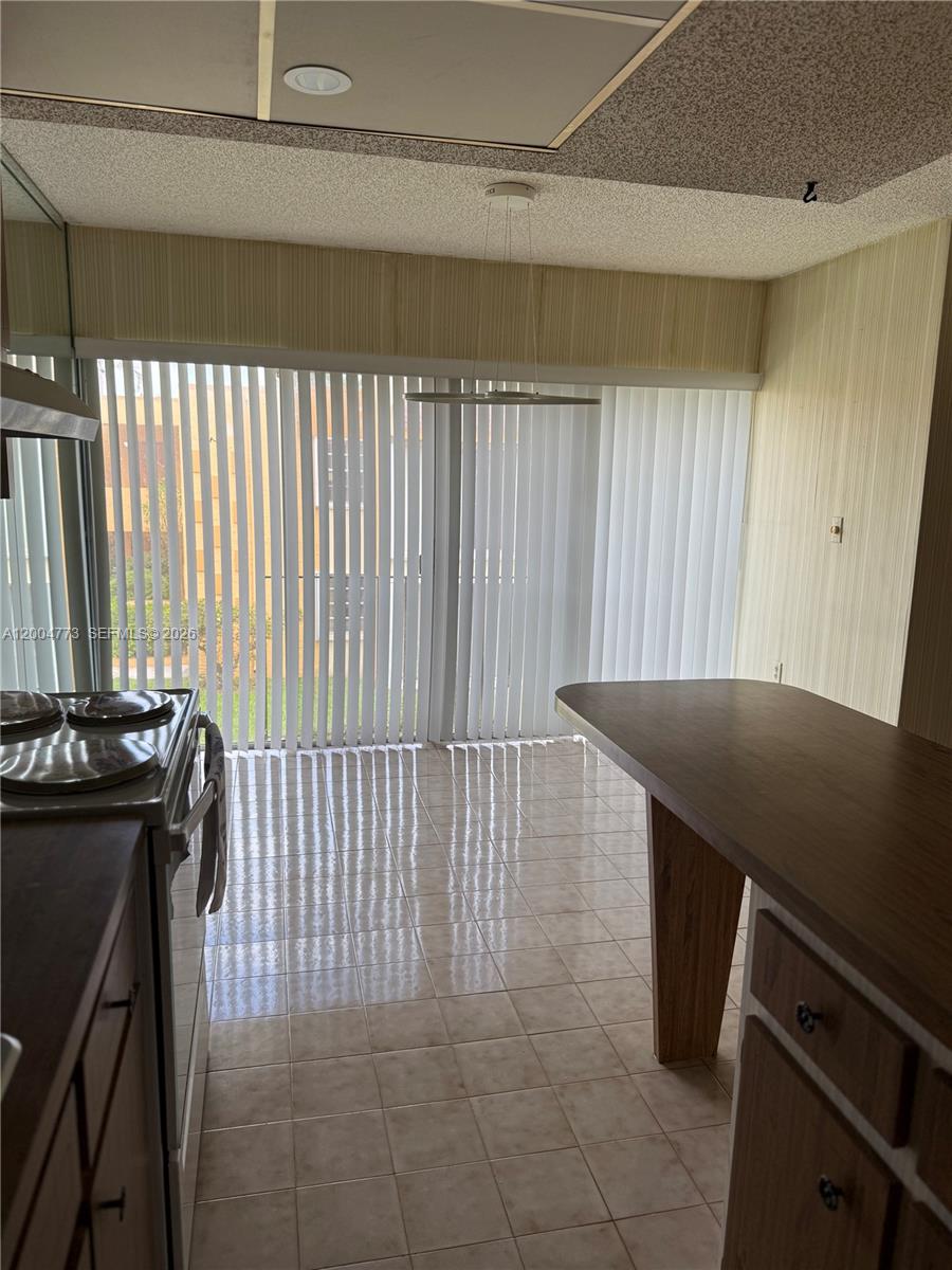 A kitchen features tiled floors, a wooden breakfast bar, and a sliding glass door — 9320 W Flagler St # 201D, Miami FL 33174, MIAMI, FL