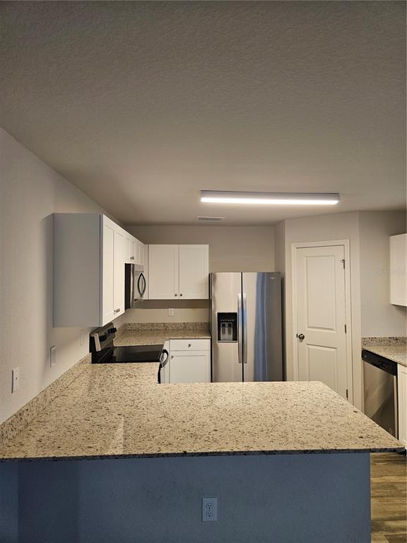 A kitchen features white cabinets, granite countertops, stainless steel appliances, and a breakfast bar — 901 NW 15TH PLACE, CAPE CORAL, FL