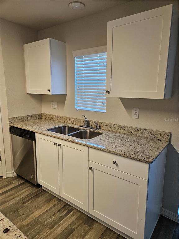 A kitchen features white cabinets, granite countertops, a stainless steel sink, and wood-look flooring — 901 NW 15TH PLACE, CAPE CORAL, FL