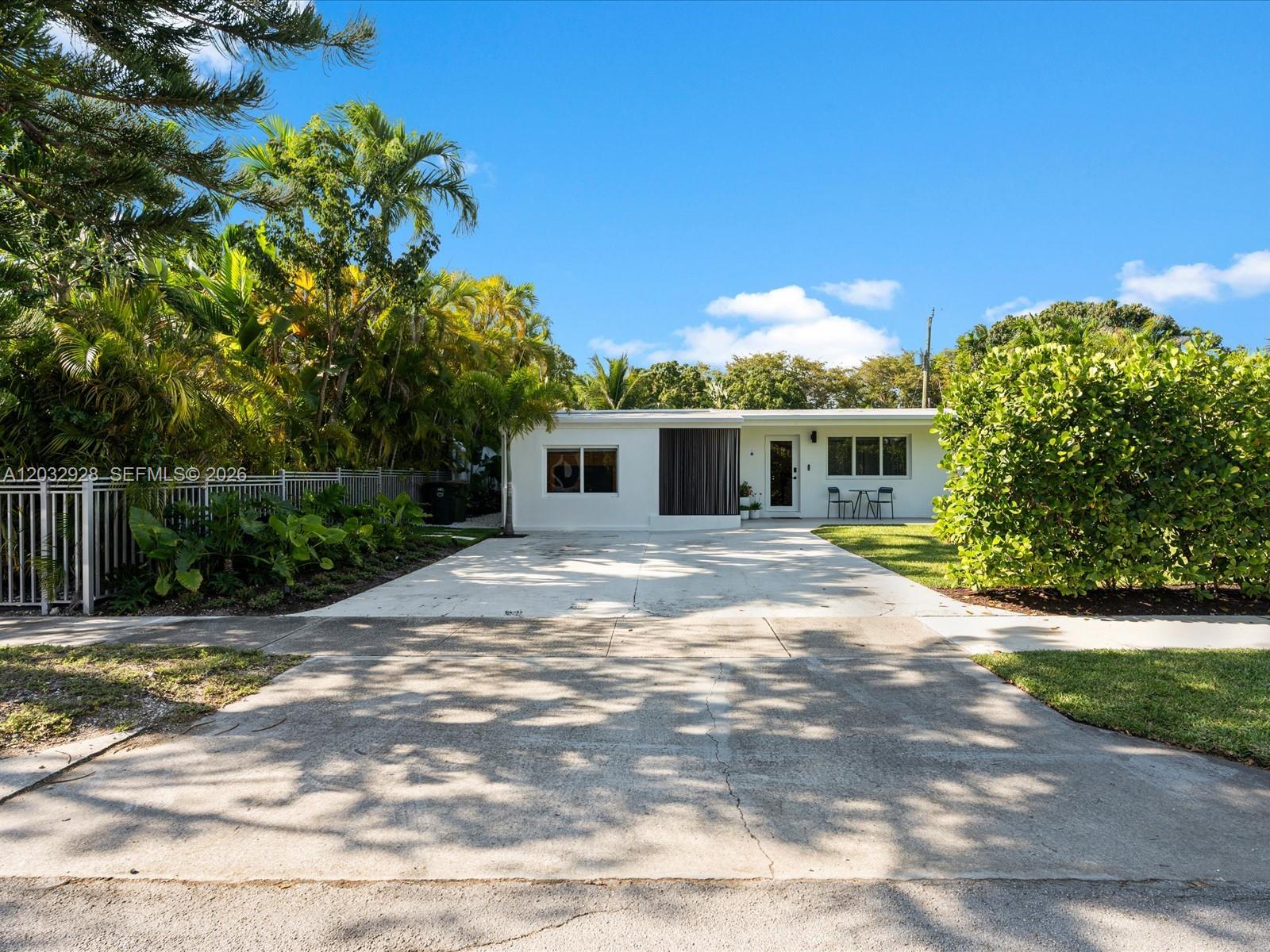 A single-story white house with a concrete driveway and lush tropical landscaping — 1945 Alamanda Dr, North Miami FL 33181, NORTH MIAMI, FL