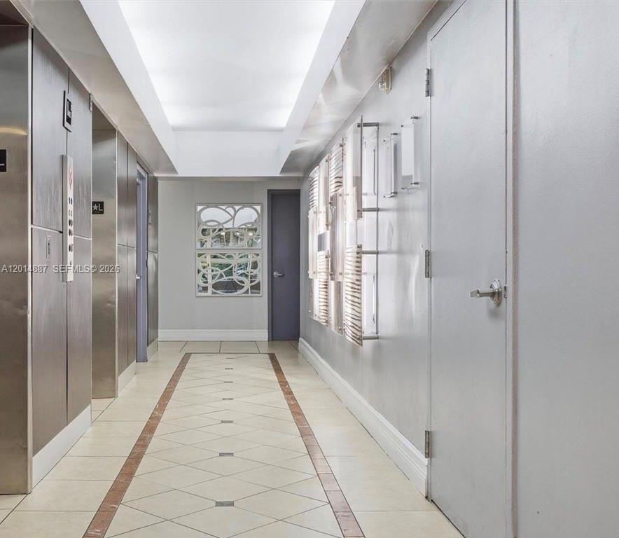 A hallway features tiled floors, metallic elevator doors, a decorative mirror, and a plain door — 800 N MIAMI AVE # 1210, Miami FL 33136, MIAMI, FL
