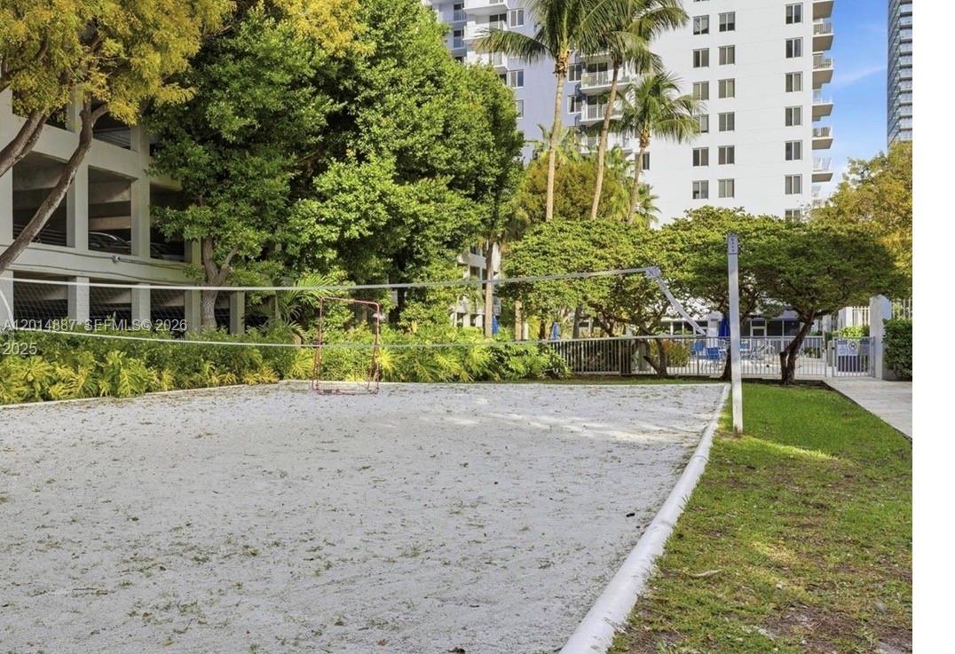 A sand volleyball court is situated outdoors next to a tall residential building and trees — 800 N MIAMI AVE # 1210, Miami FL 33136, MIAMI, FL