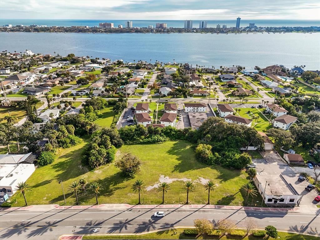 An aerial view shows a vacant grassy lot bordered by a road, trees, and residential buildings — 1771 S RIDGEWOOD AVENUE, SOUTH DAYTONA, FL