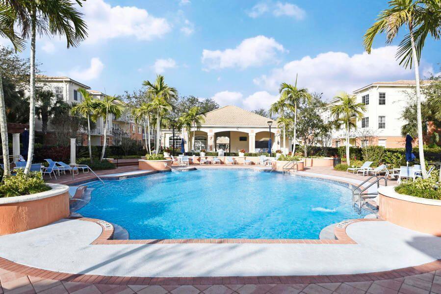 A swimming pool sits in the center of an apartment complex courtyard with palm trees — 9905 Baywinds Boulevard # 2202, West Palm Beach FL 33411, WEST PALM BEACH, FL