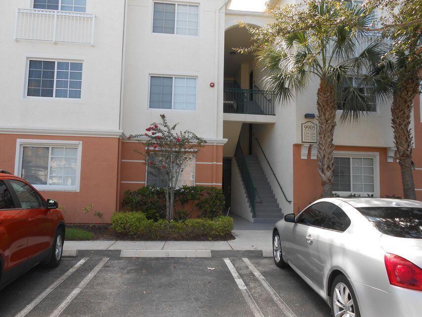The exterior of a multi-story apartment building features a staircase and parking spaces — 9905 Baywinds Boulevard # 2202, West Palm Beach FL 33411, WEST PALM BEACH, FL