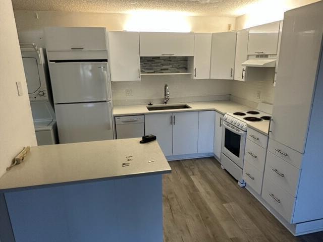 A modern kitchen features white cabinets, stainless steel appliances, and light-colored countertops — 1106 Green Pine Boulevard # E1, West Palm Beach FL 33409, WEST PALM BEACH, FL