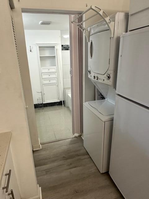 A laundry area with a stacked washer and dryer leads into a white bathroom — 1106 Green Pine Boulevard # E1, West Palm Beach FL 33409, WEST PALM BEACH, FL