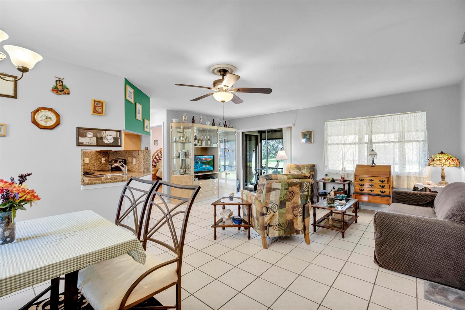 An open-concept living and dining area features tile flooring, a ceiling fan, and a kitchen pass-through — 3 Vía De Casas Sur # 102, Boynton Beach FL 33426, BOYNTON BEACH, FL