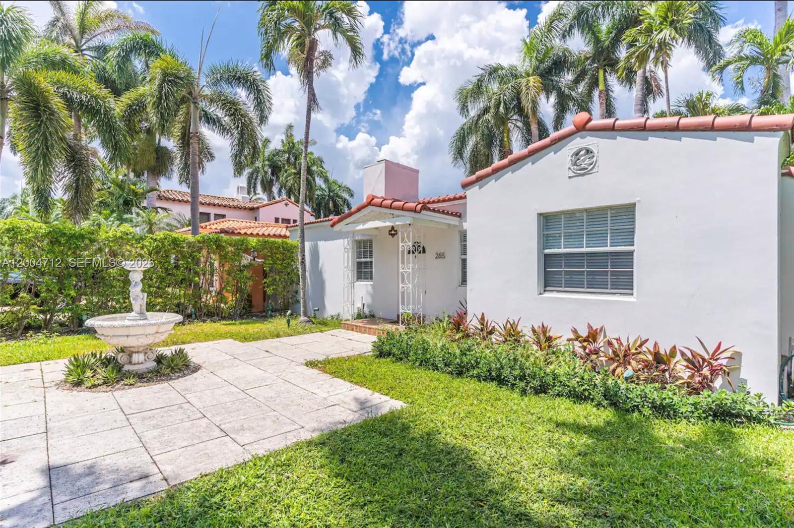 A white stucco house with a red tile roof features a front patio and fountain — 265 Palm Ave, Miami Beach FL 33139, MIAMI BEACH, FL